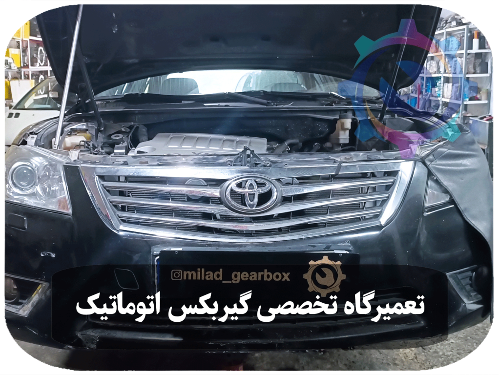 تصویری از گیربکس اتوماتیک تویوتا آریون که در حال تعمیر و نگهداری است. تکنسینان ماهر در حال ارزیابی و تعمیر این بخش بسیار حیاتی از خودرو هستند، به منظور بهبود عملکرد و عمر مفید آن.