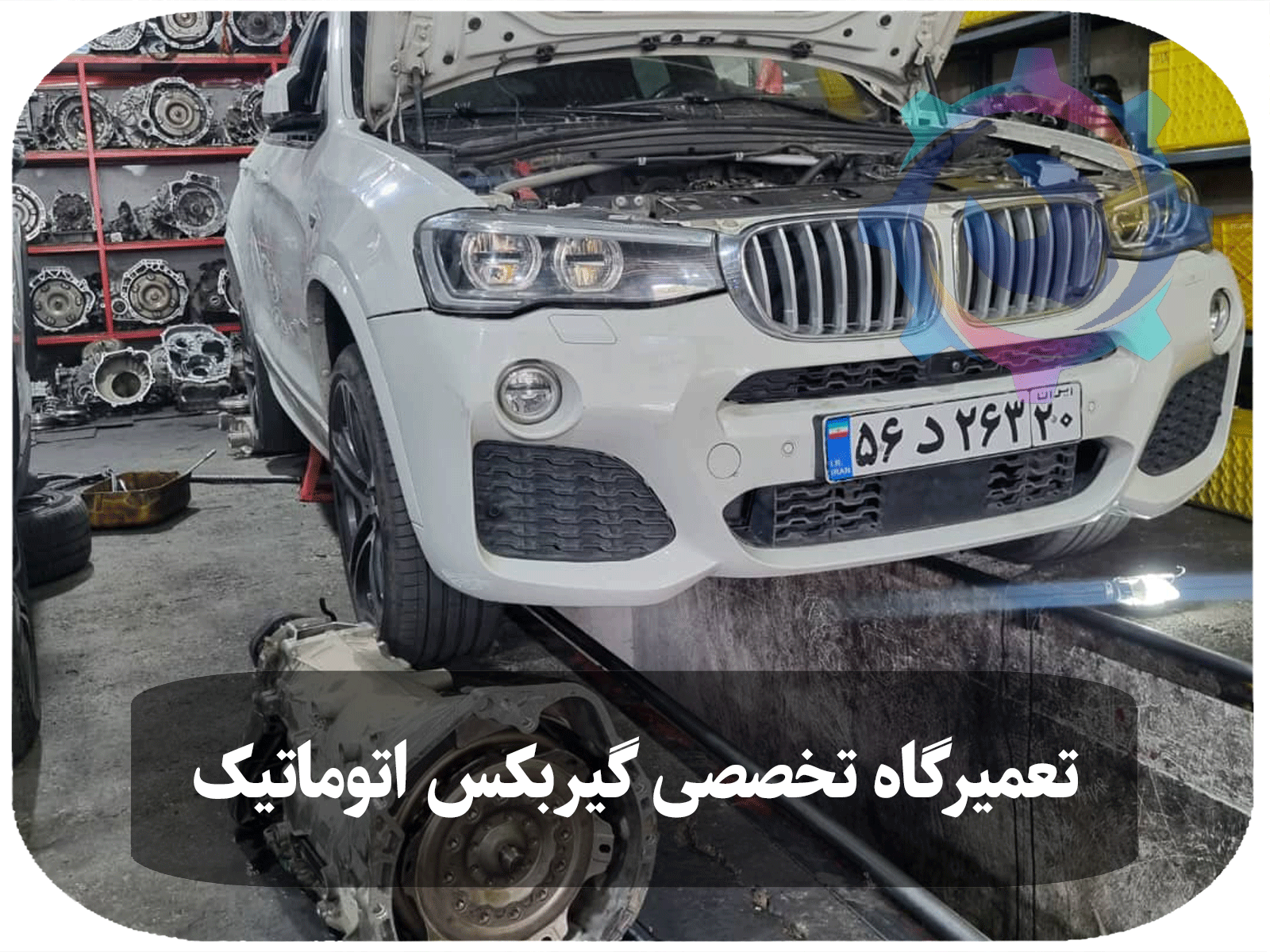 خودروی BMW X4 سفید رنگ که در حال تعمیر گیربکس اتوماتیک در تعمیرگاه تخصصی تویوکارا است. گیربکس جدا شده و در کنار خودرو قرار دارد، در حالی که خودرو روی بالابر قرار گرفته است.
